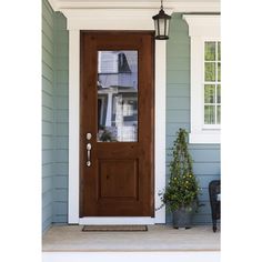 the front door is brown and has a potted plant next to it on the porch