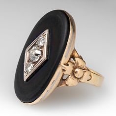 This antique statement ring is centered with one (1) oval cabochon cut natural black onyx. The onyx has been drilled at the center and topped with a white gold navette shaped setting accented with one (1) bead set, old European cut diamond and two (2) bead set, round brilliant cut diamonds. Floral details accent the shoulders of the ring. The ring measures 30.6mm at the top, rises 6.5mm above the finger, tapering to 3.5mm wide and 1.0mm thick at the base of the shank. It is currently a size 10 a Statement Rings Diamond, Bead Set, European Cut Diamonds, Oval Cabochon, Round Brilliant Cut Diamond, Statement Ring, Black Onyx, Round Brilliant, Statement Rings