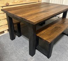 a wooden table with two benches next to it on carpeted floor in front of wall