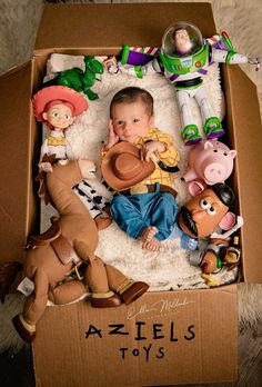 a baby in a toy story box surrounded by farm animals and other figurines