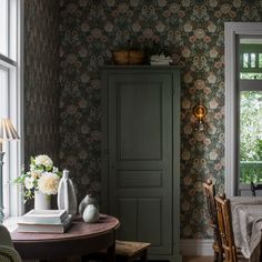 a table and chairs in a room with floral wallpaper