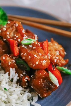 a blue plate topped with meat and rice next to chopsticks on a table