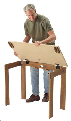 a man standing over a wooden table with two legs and a piece of wood on it