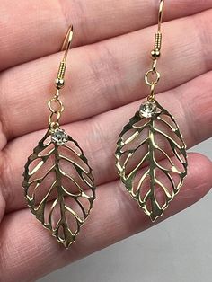 This is a pair of handmade gold toned fish hook style earrings.  They have a gold colored filigree leaf and a rhinestone charm.  The drop length is 2.25 inches. Gold Leaf-shaped Nickel-free Earrings, Gold-plated Leaf-shaped Earrings, Gold Leaf-shaped Pierced Earrings, Gold Leaf Shaped Metal Jewelry, Elegant Gold Jewelry With Fish Hook, Gold Dangle Earrings With Fish Hook, Gold Drop Earrings With Fish Hook, Gold Leaf Shaped Brass Jewelry, Gold Leaf-shaped Earrings