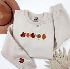 Embrace fall with our adorable Embroidered Autumn leaves sweatshirt! This cosy crewneck features vibrant embroidered leaves on the front and one on the sleeve. Perfect for a thanksgiving or halloween gift. Get yours now and spread the smiles! Check out more Fall/Thanksgiving items here: https://grumpygooseapparel.etsy.com?ref=seller-platform-mcnav§ion_id=40090396 Browse through my other awesome items here: https://www.etsy.com/shop/GrumpyGooseApparel ABOUT THE PRODUCT: Unisex Heavy Blend™ Crewneck Sweatshirt | GILDAN 18000  A sturdy and warm sweatshirt bound to keep you warm in the colder months. A pre-shrunk, classic fit sweater that's made with air-jet spun yarn for a soft feel and reduced pilling. * 50% cotton, 50% polyester * Pre-shrunk * Classic fit with no center crease * 1x1 athleti Embroidered Crew Neck Sweater For Fall, Casual Tops With Custom Embroidery For Fall, Casual Fall Sweater With Custom Embroidery, Embroidered Long Sleeve Sweatshirt For Fall, Fall Crew Neck Sweatshirt With Custom Embroidery, Crew Neck Top With Custom Embroidery For Fall, Fall Long Sleeve Sweatshirt With Custom Embroidery, Preppy Autumn, Sweatshirt Preppy