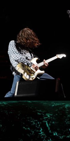 a man with long hair playing an electric guitar