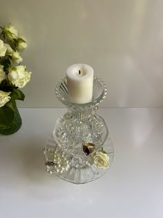 a glass candle holder with flowers and pearls