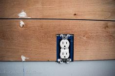 an electrical outlet on the side of a wooden wall