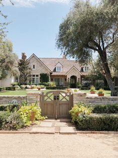 a large house with a gate in front of it and lots of bushes around the entrance