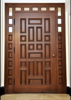 a large wooden door in front of a white wall