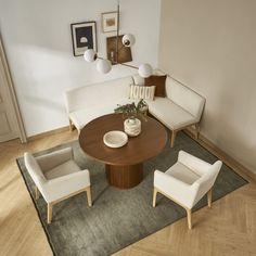 a living room with white couches and chairs around a round wooden table in the center