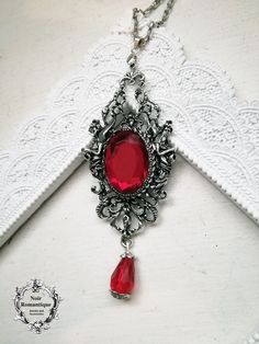 "Lucinda pendant Robert gave some of his blood to Lucinda for her to drink.\" Iris was perplexed by this . \"What for?\" she asked. \"To change her into one of us, into a vampire... A mesmerizing pendant holding a ruby red gem 18x25mm" Gothic Dangle Necklaces For Parties, Collectible Gothic Metal Necklace, Handmade Gothic Dangle Necklaces, Gothic Pendant Necklace For Party, Halloween Gothic Pendant Necklace, Gothic Pendant Necklace For Halloween, Gothic Dangle Necklaces As Gifts, Gothic Dangle Necklace For Gift, Gothic Dangle Necklaces For Gifts