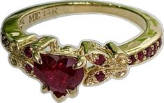 a gold ring with a heart shaped red stone in the center and two smaller hearts on each side