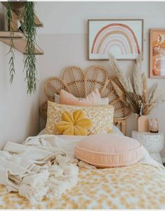 a bed with pillows and blankets on top of it in a room filled with pictures