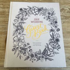 the wedding guest book is sitting on a wooden table with flowers and lettering that reads our wedding guest book