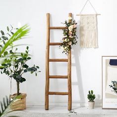 a ladder leaning against a wall next to potted plants and a framed photograph with flowers on it