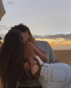 a man and woman kissing on the beach