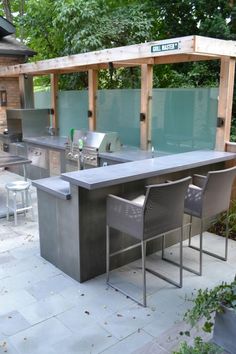 an outdoor kitchen with grills and chairs