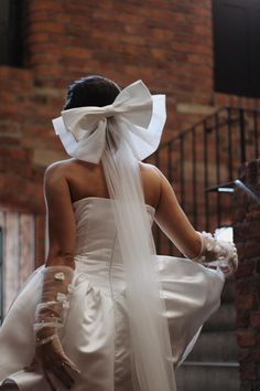 a woman in a white wedding dress with a veil on her head is walking down the stairs