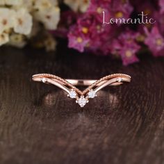 a rose gold wedding band with three diamonds on it and the words romantic written in cursive font