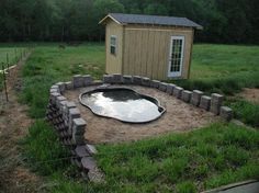 a small pond sits in the middle of a yard with a shed and fence around it