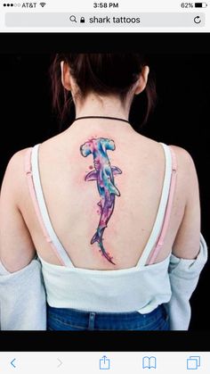 a woman with a tattoo on her back is looking down at the watercolor dolphin