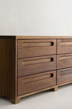 a close up of a wooden dresser on a white floor with a wall in the background