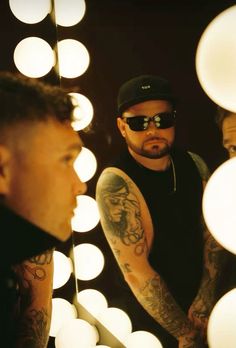 a man is looking at himself in the mirror with his arm tattoos and sunglasses on