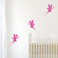 two pink fairy tinkerbells flying over a crib in a nursery room