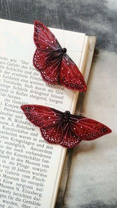 two red butterflies sitting on top of an open book