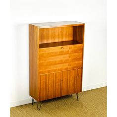 a wooden cabinet sitting on top of a carpeted floor next to a white wall