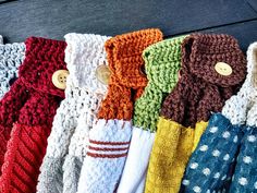 many different colored knitted mittens are lined up on a table with wooden buttons