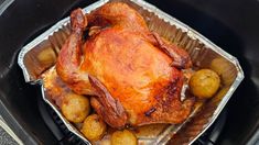 a roasting turkey in an air fryer pan with potatoes and other food items