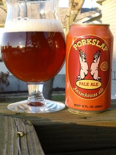 a glass full of beer sitting on top of a wooden table