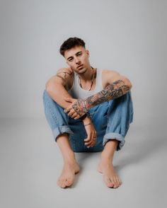 a man with tattoos sitting on the ground