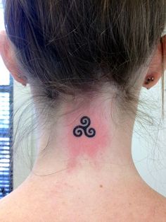 a woman's neck with a tattoo on the back of her neck, which has an image of two spirals