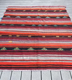 a multicolored striped rug sitting on top of a wooden floor