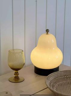 a table topped with a lamp next to a bowl and glass vase on top of it