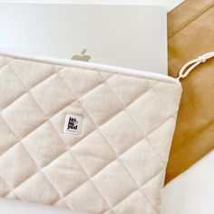 an open laptop computer sitting on top of a white case next to a brown bag