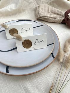 two place cards are sitting on a plate with some dried grass in front of them