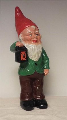 a gnome figurine holding a black box with a red hat and green jacket