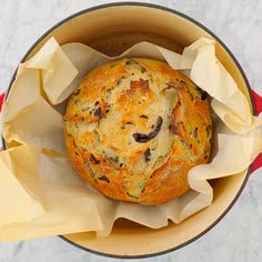 a baked item in a red pot on a marble counter top, with tissue paper around it