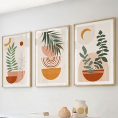 three framed art prints hanging on the wall above a table with vases and books