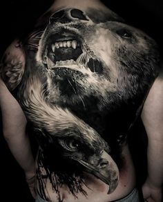 a man's back is covered in tattoos with an image of two bears attacking each other