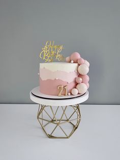 a pink and gold birthday cake on a stand