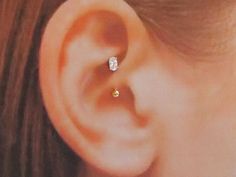 a woman's ear with two small diamond studs