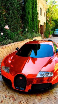 a red sports car parked on the side of a road next to a brick wall