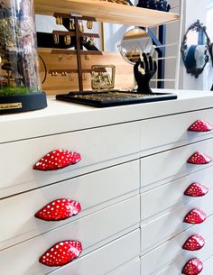 a white dresser with red polka dot knobs on it's drawers and shelves