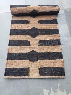 a black and tan striped rug laying on top of a cement floor next to a roll of jute