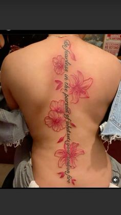 the back of a woman's body with pink flowers on it and an inscription that reads